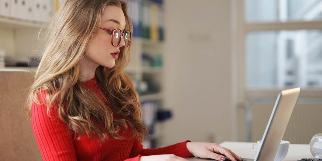 A woman in a red pullover working productively in her home office