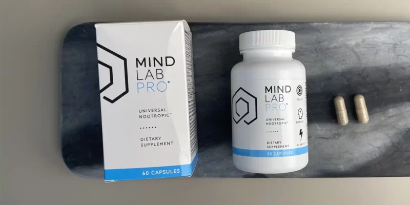 A package of Mind Lab Pro and a bottle of Mind Lab Pro lying next to 2 capsules
