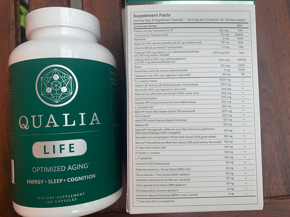 One bottle of Qualia Life next to the packaging box of Qualia Life which states the Supplement Facts and ingredients