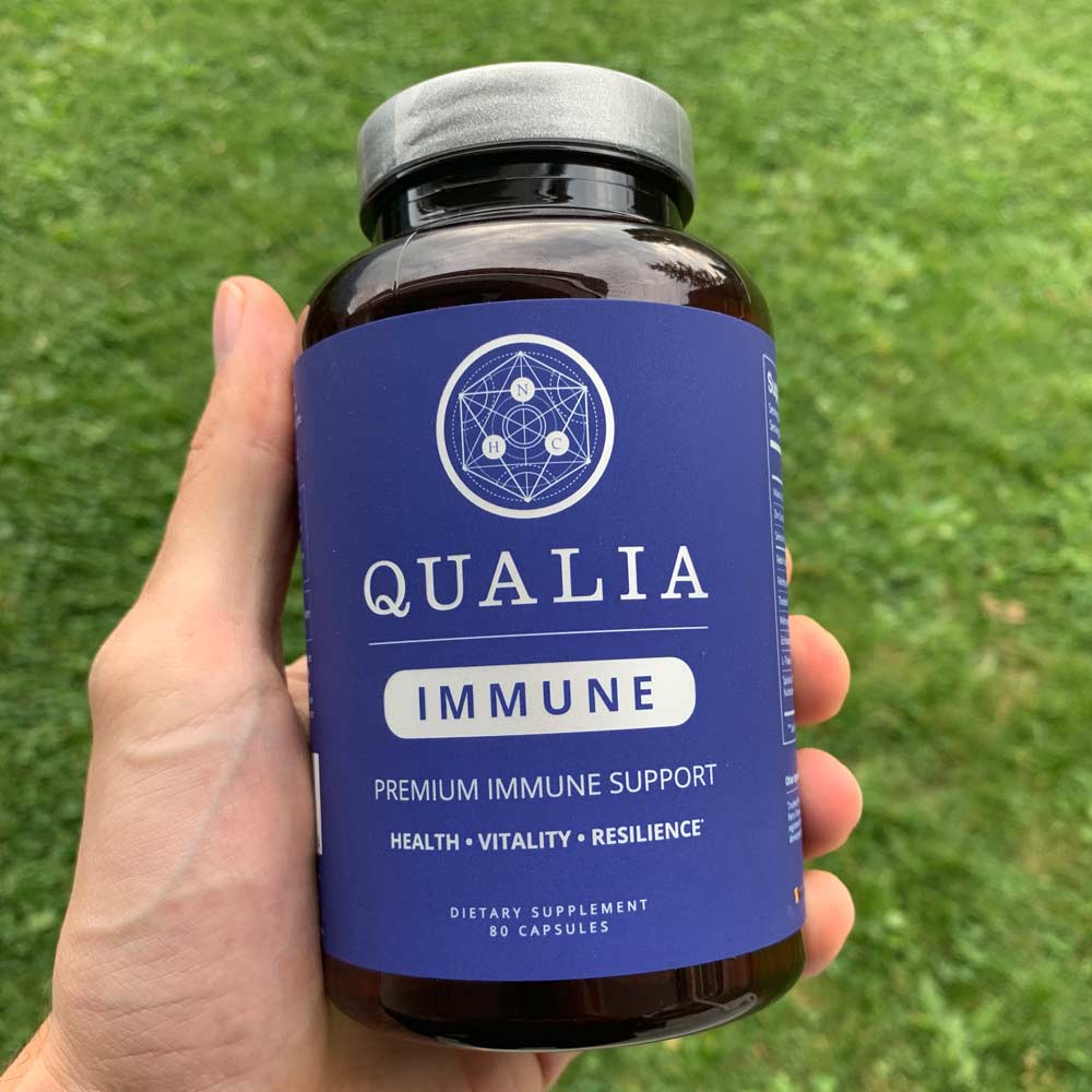 A hand holding a bottle of Qualia Immune