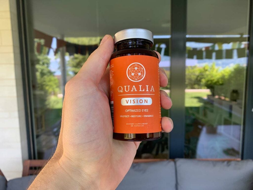 A hang holding a bottle of Qualia Vision