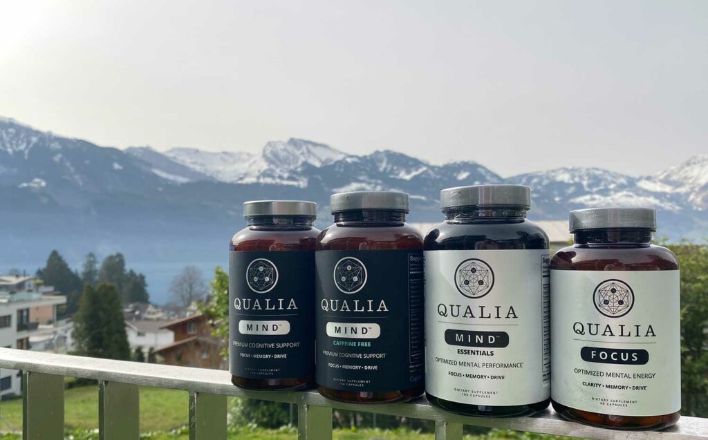 Bottles of Qualia Mind, Qualia Mind Caffeine Free, Qualia Mind Essentials, and Qualia Focus against a backdrop of Mountains