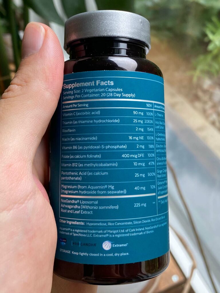 A hand holds a bottle of Qualia Resilience showing the ingredient list table