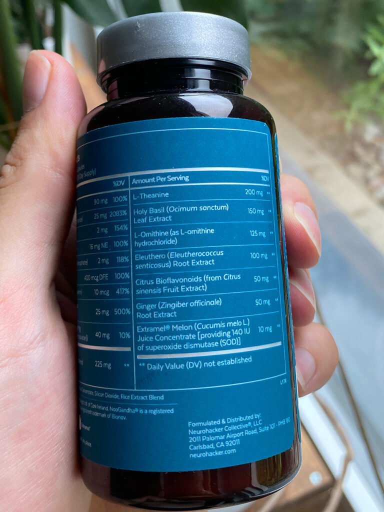 A hand holds a bottle of Qualia Resilience showing the ingredient list table