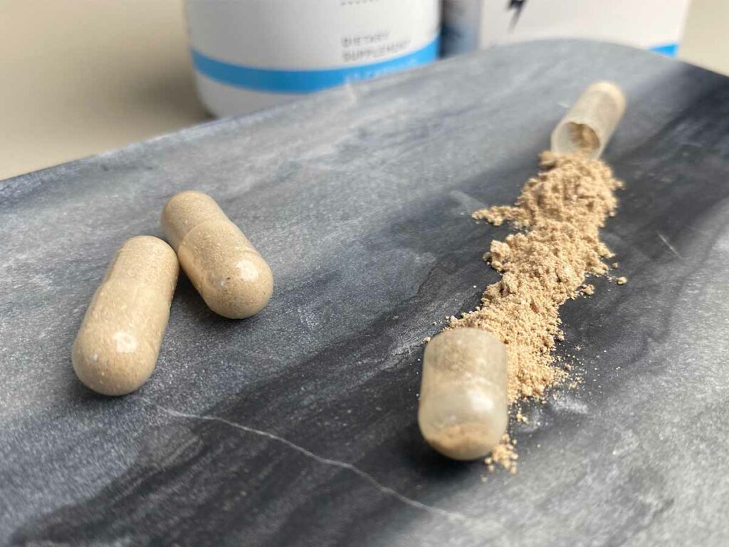 A capsule of Mind Lab Pro opened with powder lying on a marble tray.