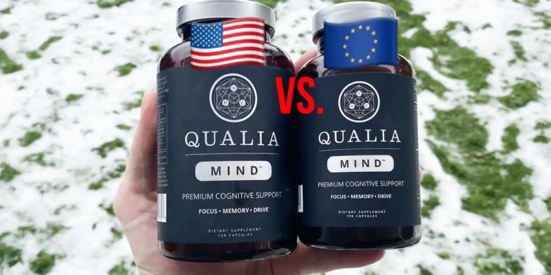 A hand holding one bottle of Qualia Mind US and one bottle of Qualia Mind EU