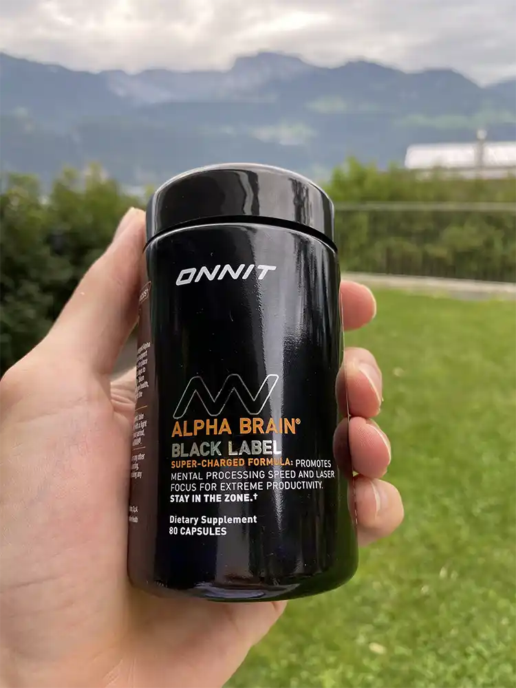 A hand holding a bottle of Onnit Alpha Brain Black Label