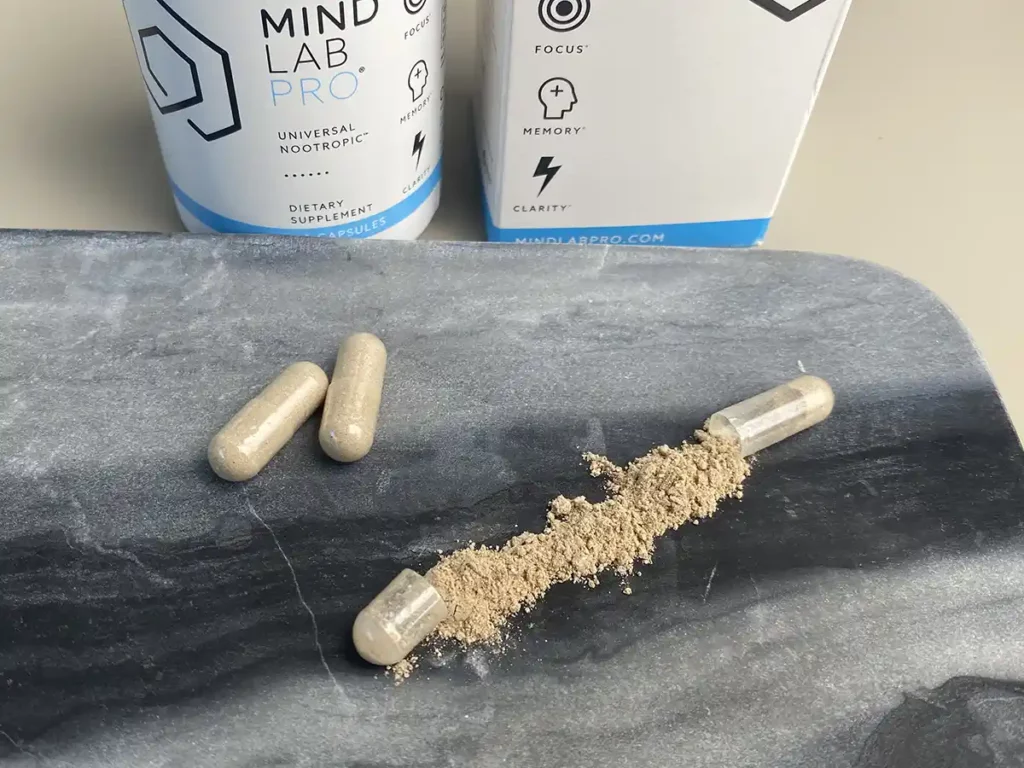 Zwei Kapseln von Mind Lab Pro und eine geöffnete Kapsel von Mind Lab Pro liegen auf einem Marmor Tablett