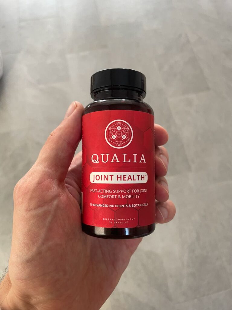 My hand holding a bottle of Qualia Joint Health